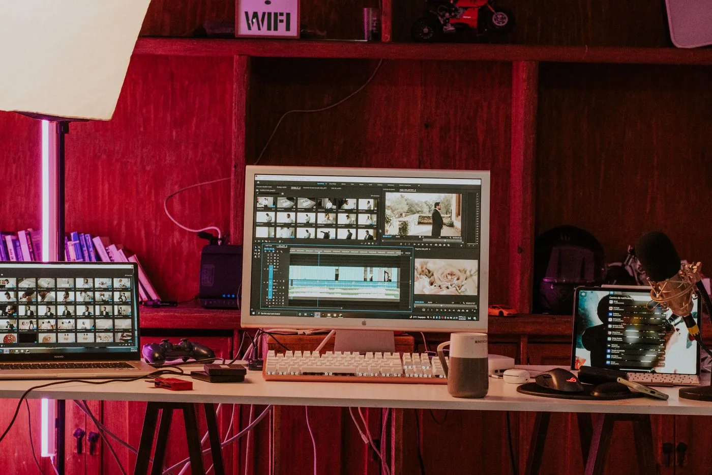 A creative editing workspace with several monitors and a laptop